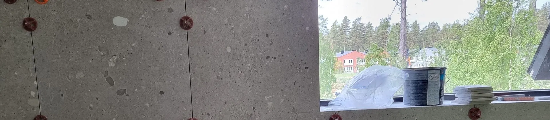 Nysatta väggplattor med kilar i fogarna framför ett fönster